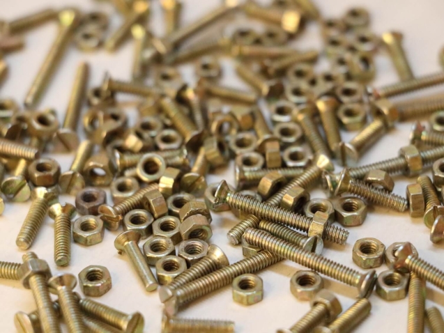 Metalowe śruby i nakrętki na białym tle