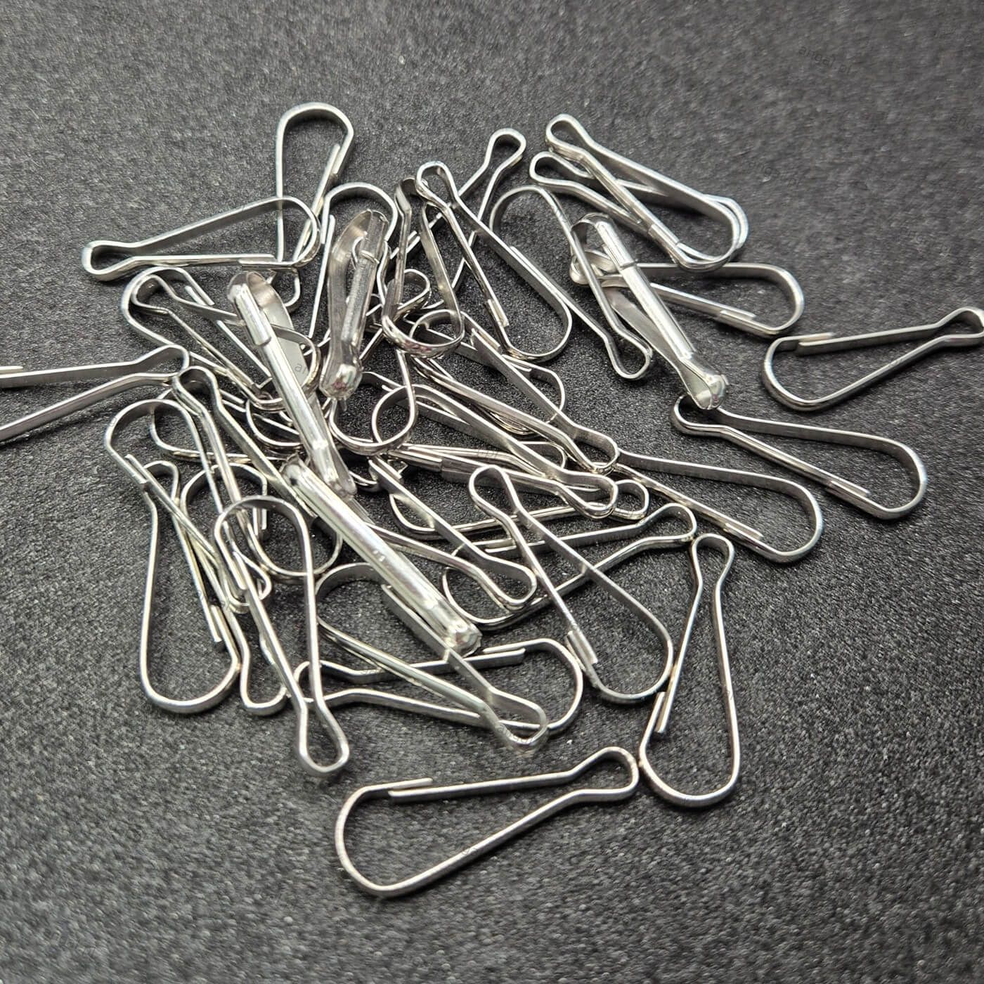 Srebrne spinacze biurowe na szarym tle